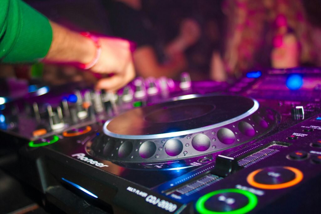 Close-up of a DJ's hands on mixing console at a vibrant party in Utrecht.