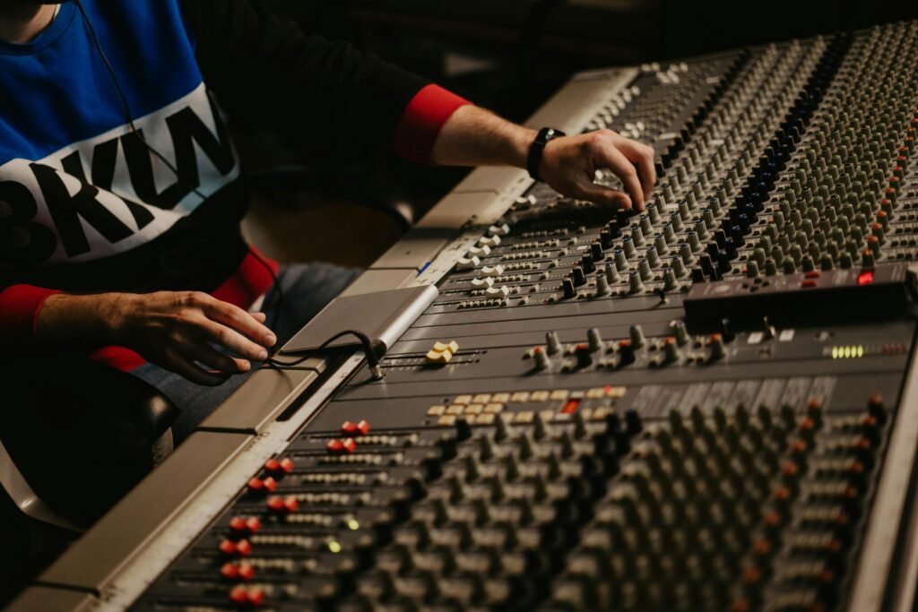 Sound engineer adjusting audio levels on a mixing console in a modern recording studio.