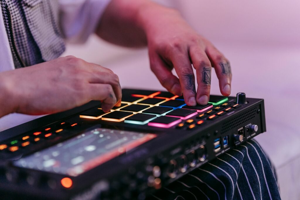 Tattooed hands operating a colorful music sequencer in a creative indoor setting.