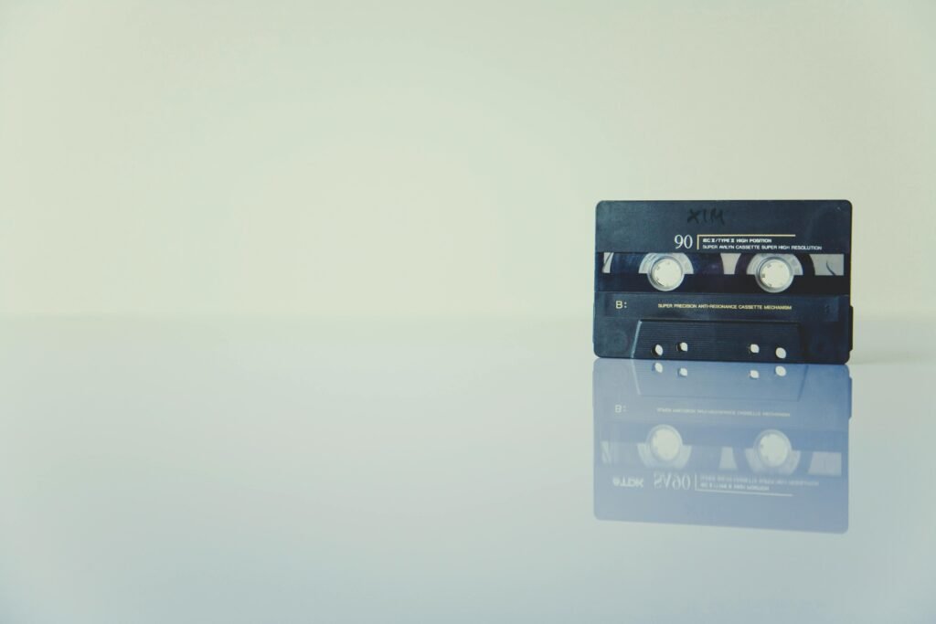 Retro cassette tape on a reflective surface, evoking nostalgia and vintage music vibes.